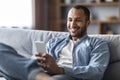 Mobile Communication. Handsome Black Man Messaging On Smartphone While Relaxing At Home Royalty Free Stock Photo
