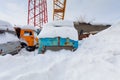 Mobile construction crane with hook and some trucks are in the snowdrift Royalty Free Stock Photo