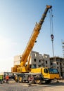 A mobile construction crane is positioned on a construction site with a backdrop of Royalty Free Stock Photo