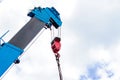 Mobile construction cranes with red lifting steel crane hook, swivel joint and connection steel sling in sunny day with clouds bac