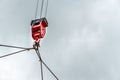 Mobile construction cranes with red lifting steel crane hook, swivel joint and connection steel sling in sunny day with clouds bac