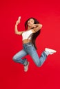 always on mobile. Full length of pretty young woman taking phone while jumping against red studio background. Royalty Free Stock Photo
