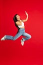 always on mobile. Full length of pretty young woman taking phone while jumping against red studio background. Royalty Free Stock Photo