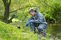 Mobile laboratory specialist in a protective suit does a water analysis on the river bank