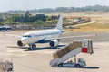 Mobile ladder and an arriving plane with passengers on the apron of the airfield Royalty Free Stock Photo