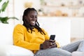Mobile Messaging. Black Guy Using Smartphone While Resting In Chair At Home Royalty Free Stock Photo