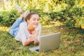 Mobile Office. Freelance business concept. Young woman lying on green grass lawn in city park working on laptop pc computer. Royalty Free Stock Photo