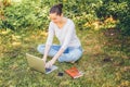 Mobile Office. Freelance business concept. Young woman sitting on green grass lawn in city park working on laptop pc computer. Royalty Free Stock Photo