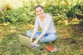Mobile Office. Freelance business concept. Young woman sitting on green grass lawn in city park working on laptop pc computer. Royalty Free Stock Photo
