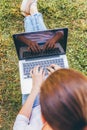 Mobile Office. Freelance business concept. Young woman sitting on green grass lawn in city park working on laptop pc computer. Royalty Free Stock Photo