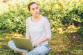 Mobile Office. Freelance business concept. Young woman sitting on green grass lawn in city park working on laptop pc computer. Royalty Free Stock Photo