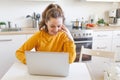 Mobile Office at home. Young woman sitting in kitchen at home working using on laptop computer. Lifestyle girl studying Royalty Free Stock Photo