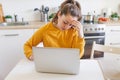 Mobile Office at home. Young woman sitting in kitchen at home working using on laptop computer. Lifestyle girl studying Royalty Free Stock Photo