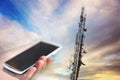 Mobile phone aiming at telecommunication tower Royalty Free Stock Photo