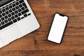 Mobile phone with blank white mockup touchscreen and laptop computer on office desk, top view Royalty Free Stock Photo