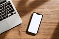 Mobile phone with blank white mockup touchscreen and laptop computer on office desk, top view Royalty Free Stock Photo