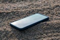 Mobile phone buried in the grey sand, lose your smartphone on the beach while on vacation a