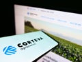 Mobile phone with business logo of US agricultural chemical company Corteva Inc. on screen in front of website.