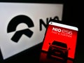 Mobile phone with business webpage of Chinese electric car manufacturer NIO Inc. on screen in front of logo.