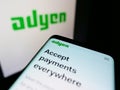 Mobile phone with business website of Dutch payment services company Adyen N.V. on screen in front of logo.