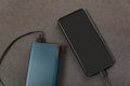 Mobile phone charging with energy bank. Power bank and smartphone with blank screen on grey background. Power-saving device and Royalty Free Stock Photo