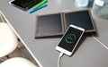 Mobile phone charging with portable solar panel over office desk Royalty Free Stock Photo