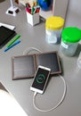 Mobile phone charging with portable solar panel and selective trash bins over desk in classroom Royalty Free Stock Photo