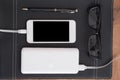 Mobile phone charging from power bank, eyeglasses and pen on the Royalty Free Stock Photo