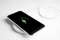 Mobile phone charging with wireless pad on white table Royalty Free Stock Photo