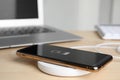 Mobile phone charging with wireless pad on table, closeup. Space for text Royalty Free Stock Photo