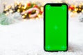 Mobile phone with chromo key on the screen with copy space on the Christmas decoration background. Royalty Free Stock Photo