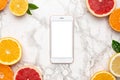 Mobile phone and citruses on marble background, fruit flatlay, summer minimal compositon with grapefruit, lemon, mandarin and