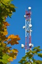 Mobile phone communication radio tv tower, mast, cell microwave antennas and transmitter against the blue sky and trees Royalty Free Stock Photo