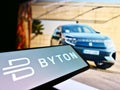 Mobile phone with company logo of Chinese automotive brand Byton (electric vehicle) on screen in front of web page.