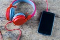 Mobile phone connecting with red headphone over the keyboard. Royalty Free Stock Photo