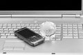 Mobile phone and glass globe on laptop keyboard