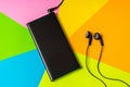 Mobile phone with headphones isolated on colorful background Royalty Free Stock Photo