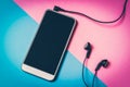 Mobile phone with headphones isolated on colorful background Royalty Free Stock Photo