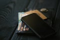 A mobile phone laying on a leather purse and small stack of coins on black wooden table, Royalty Free Stock Photo