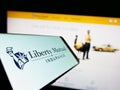 Mobile phone with logo of American insurance company Liberty Mutual Group on screen in front of website.