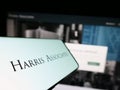 Mobile phone with logo of American investment company Harris Associates L.P. on screen in front of website.