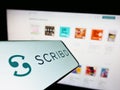 Mobile phone with logo of American publishing platform company Scribd Inc. on screen in front of website.