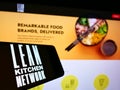 Mobile phone with logo of British company Lean Kitchen Network Limited (LKN) on screen in front of website. Royalty Free Stock Photo