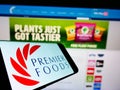Mobile phone with logo of British food manufacturer Premier Foods plc on screen in front of company webpage.