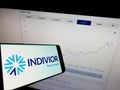 Mobile phone with logo of British pharmaceutical company Indivior plc on screen in front of website.