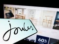 Mobile phone with logo of British retail company Joules Group plc on screen in front of business website.