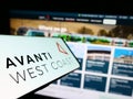 Mobile phone with logo of British train company Avanti West Coast on screen in front of business website.