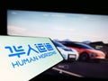 Mobile phone with logo of Chinese company Human Horizons Technology on screen in front of business website.