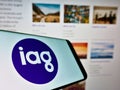 Mobile phone with logo of company Insurance Australia Group Limited (IAG) on screen in front of website.