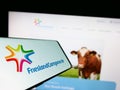 Mobile phone with logo of company Koninklijke FrieslandCampina NV on screen in front of business website.